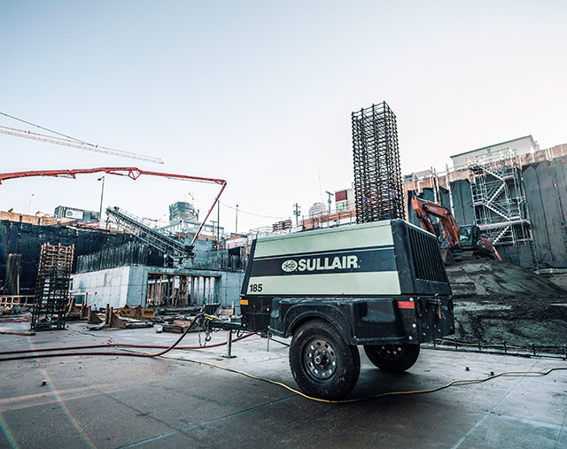 A Sullair 185 portable diesel air compressor on a construction job site